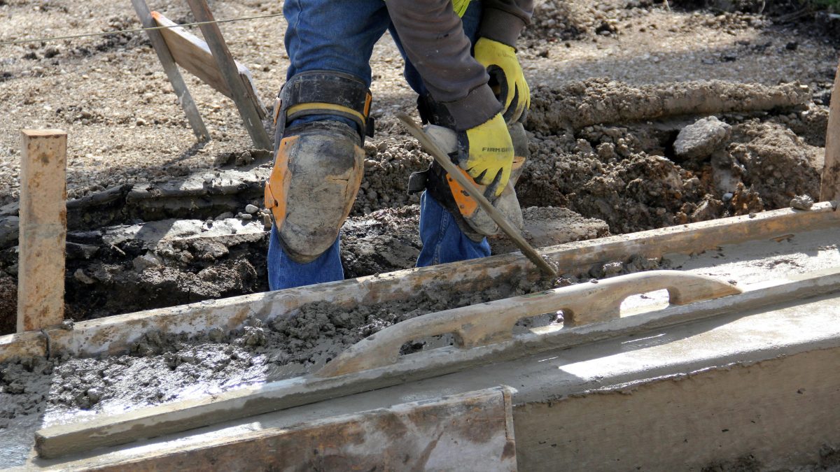 Worker wearing safety boots and leg protection on construction site.
